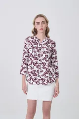 Camisa holgada de viscosa con estampado floral en tonos blanco y marrón rojizo. Presenta cuello mao y mangas tres cuartos con puños sencillos. Incluye dos bolsillos de parche en el pecho.