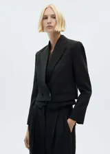Blazer corto negro con solapas de satén, doble botonadura y bolsillos de ribete.
