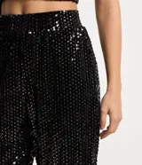 Pantalón jogger de lentejuelas negras con cintura elástica y puños ajustados.
