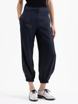 Pantalón negro de viscosa con ligero brillo, estilo babucha, con cintura alta y puños ajustados con elástico en los tobillos. Posee bolsillos diagonales delanteros y ojales traseros.