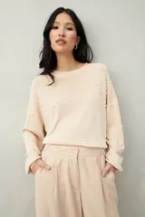 Sweater color beige con cuello redondo y mangas largas. Decorado con perlas sintéticas en forma de rombos.
