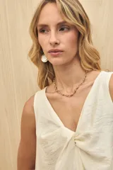 Vestido midi color crudo, sin mangas, con escote en V y detalle de nudo en el frente.