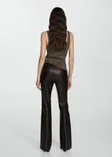 Pantalón negro de efecto piel, tiro medio, corte flare y cinco bolsillos.