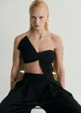 Top negro con tirantes finos, diseño crop y lazo en el frente.