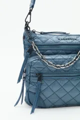 Cartera bandolera azul con diseño matelassé, cadena metálica decorativa y dos correas desmontables. Cuenta con cierre superior y múltiples bolsillos internos.