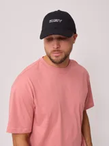Gorra de lona color salmón con logo de la marca bordado en blanco.