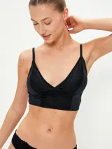 Conjunto de ropa interior negro, compuesto por un bralette de encaje con breteles finos y una bombacha tipo colaless de encaje.