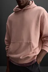Sudadera con capucha color rosa viejo, confeccionada en tejido de algodón. Tiene cuello con capucha ajustable, manga larga, bolsillo tipo canguro y logo bordado en el pecho.