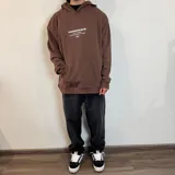 Canguro marrón con capucha y cordones ajustables. Estampado en la espalda con texto en blanco y naranja, y dibujo de un pulpo. Corte oversize.