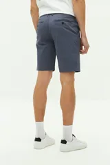 Bermuda de gabardina azul marino con logo bordado, bolsillos laterales y traseros, cierre con cremallera y botón, y presillas para cinturón.