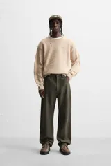 Sweater color beige con detalles de roturas y agujeros.