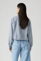 Camisa a rayas verticales azules y blancas, con cuello clásico, cierre frontal con botones y dos bolsillos de parche en el pecho.