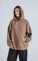 Hoodie marrón de algodón rústico con silueta oversize, capucha forrada, bolsillo tipo canguro y bolsillo en la manga con cierre.