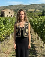 Chaleco corto negro con bordados botánicos en hilo color arena/dorado, sin mangas y con escote en V.