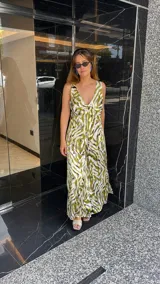 Vestido largo estampado con escote en V profundo y tirantes anchos. El diseño presenta un frunce o nudo en el centro del busto y tajos laterales en la falda.