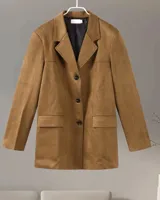 Blazer marrón de gamuza con solapas de muesca, cierre con dos botones y bolsillos con solapa.