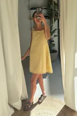 Vestido corto amarillo con estampado vichy, de corte suelto con tirantes finos con lazo.