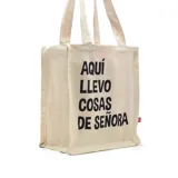 Bolso tipo tote bag de tela color crudo con asas cortas y estampado negro con la frase "Aquí llevo cosas de señora".