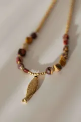 Collar dorado con cadena de eslabones y cuentas de piedra en tonos marrones, rojas y beige. Dije colgante de acero quirúrgico con forma de sardina.