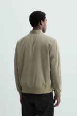Cazadora bomber ligera gris confeccionada en tejido técnico. Cuello y puños en rib elástico, manga larga, bolsillos de vivo en cadera y bolsillo interior. Cierre frontal con cremallera.