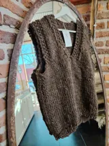 Chaleco tejido de lana color marrón con cuello en V y sisas amplias. Tejido de punto grueso.