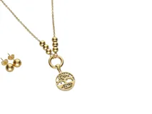 Set de collar y caravanas de acero con baño de oro. El collar tiene una cadena con cuentas y un dije circular con el diseño del árbol de la vida. Las caravanas son aros tipo botón con forma de esfera.