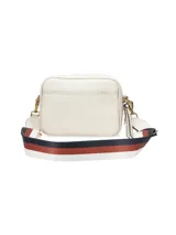 Cartera bandolera de cuero sintético color blanco con logo dorado en el frente. Tiene correa ancha de tela estampada con motivos geométricos y herrajes dorados. Incluye un dije de flecos de cuero en el lateral.