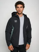 Campera corta de abrigo Umbro Crafted Pro, color negro con paneles laterales en gris. Presenta capucha con cordón ajustable, cierre frontal completo y logo de la marca bordado en el pecho.