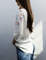 Blusa azul con escote redondo, mangas 3/4 con bordado floral y abertura central con botones. Marca Forgotten Grace.