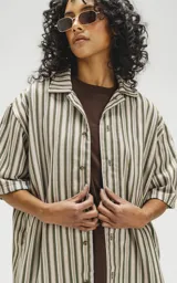 Camisa oversize de manga corta con cuello abierto y estampado a rayas verticales en tonos verde y beige.