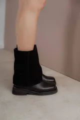 Bota corta de cuero negro, con caña baja de gamuza y suela track.