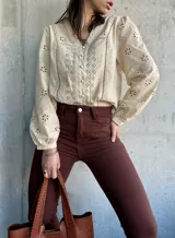 Camisa color manteca con bordado inglés, cuello en V y mangas largas abullonadas.
