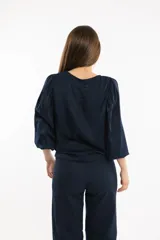 Blusa azul marino con cuello bote y mangas amplias con elástico en los puños.