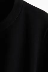 Remera de manga corta en punto fino de mezcla de viscosa, color negro. Presenta escote redondo, puños y bajo en punto acanalado.