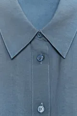 Camisa rosa claro confeccionada en hilatura con modal, de corte holgado, con cuello solapa, manga larga terminada en puño, dos bolsillos con solapa en el delantero y cierre frontal con botones.