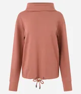 Polera hecha en tela canalé con tacto peluche, color ladrillo, con cuello alto, mangas largas y lazo en el bajo.
