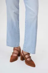 Zapato de cuero marrón con taco bloque, punta fina y dos tiras con hebillas doradas.