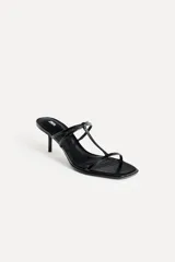 Sandalias de tacón fino color negro charol, con tiras delgadas en el empeine y punta cuadrada.