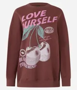 Buzo marrón de algodón con forro de polar, corte oversize, cuello redondo y mangas largas. Estampa frontal con la frase "Love Yourself" en color rosa y dibujo de cerezas.
