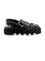 Sandalia de cuero negro con diseño entrelazado y suela gruesa.