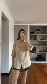 Camisa color beige de muselina con cuello clásico, corte holgado y mangas 3/4 con botón para sujetar.