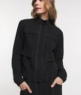 Campera bomber negra de viscosa con cierre delantero, bolsillos con solapa y pespuntes contrastantes en color blanco.