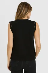 Musculosa negra con cuello redondo, sin mangas, con apliques de tachas en los hombros.