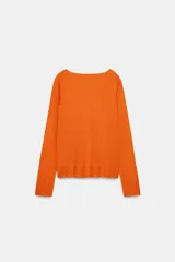 Jersey de punto liso, color azul brillante, con cuello redondo y manga larga. Presenta acabados en rib en puños, cuello y bajo, con aberturas laterales en el ruedo.