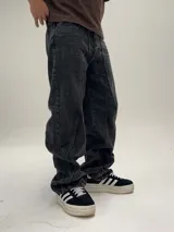 Pantalón de jean negro con efecto lavado, corte amplio tipo baggy y costuras verticales en el frente.