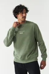 Buzo verde oliva de felpa con cuello redondo, puños y cintura acanalados. Estampado frontal con la frase "The Real Balance" en letras blancas y logo de la marca Mistral.