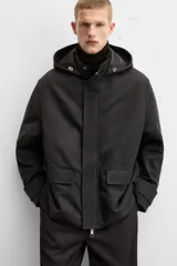 Parka negra de corte regular, confeccionada en tejido técnico acolchado. Tiene cuello alto con capucha ajustable, mangas largas con puños ajustables, bolsillos con solapa en la cadera y un bolsillo interior. El cierre frontal es con cremallera oculta por solapa con botones a presión.