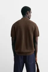 Polo gris de punto con textura, corte regular, cuello solapa y cierre frontal con botones.