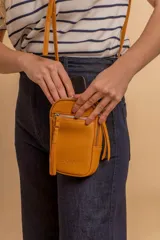 Bandolera compacta de símil cuero color rojo, con correa regulable y desmontable. Posee apertura superior, bolsillo frontal con cierre y bolsillo trasero abierto.