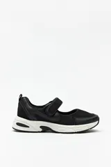 Zapatillas deportivas negras con suela blanca de 4cm de alto y tira ajustable con velcro.